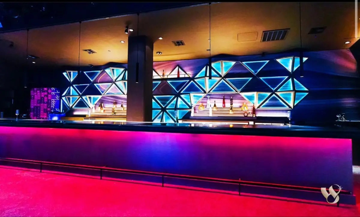 The back bar at West 8: triangle LED wall over a hot pink bar front